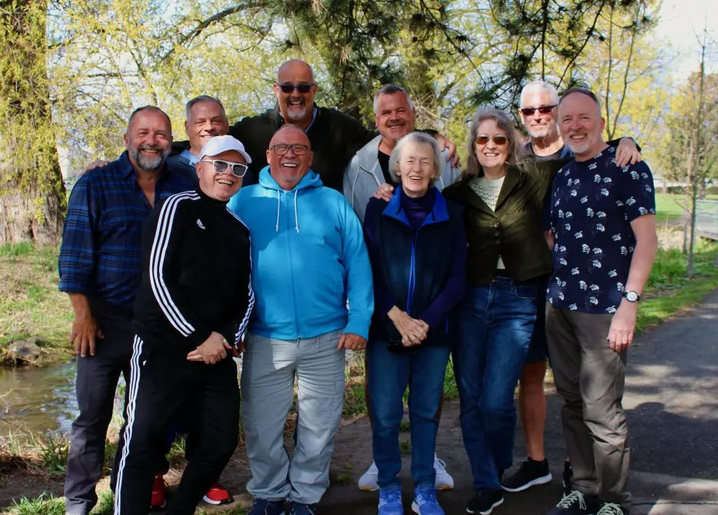 A group of seniors standing together outside under a tree.